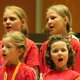 Nahaufnahme von vier singenden Mädchen in roten T-Shirts.